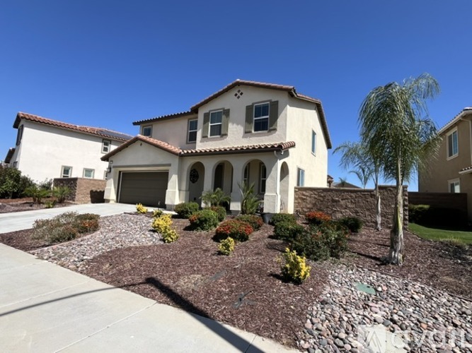 A house with a red tile roof and a stone wall in front.