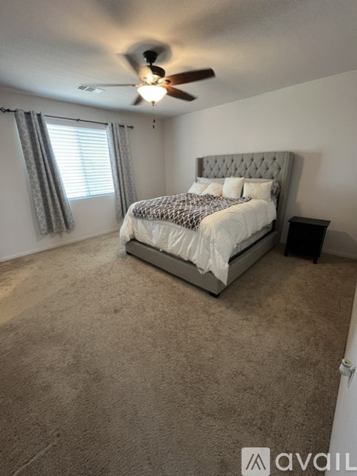 A bedroom with a large bed and a ceiling fan.