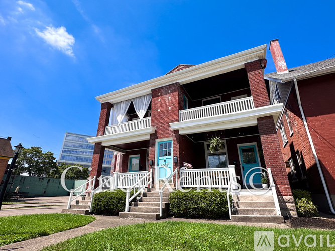 A red brick house with a blue door and a white porch.