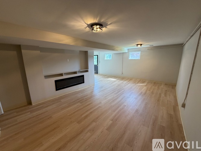 A spacious room with wooden flooring and a fireplace.