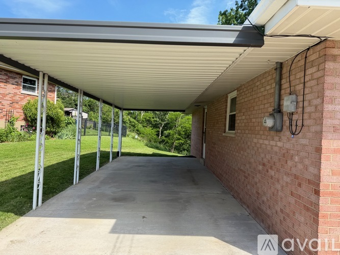 A covered walkway leads from a brick building to a grassy area.