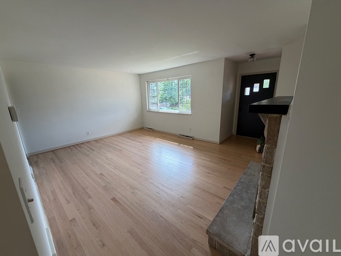 A room with wooden flooring and a window letting in natural light.