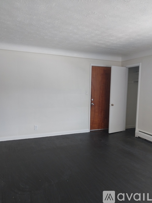 A room with a wooden door and a white wall.