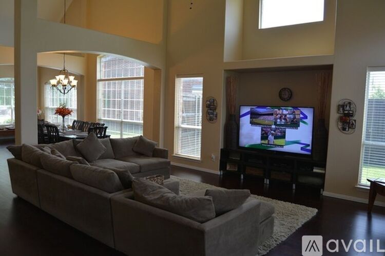 A living room with a large couch and a television playing a sports game.