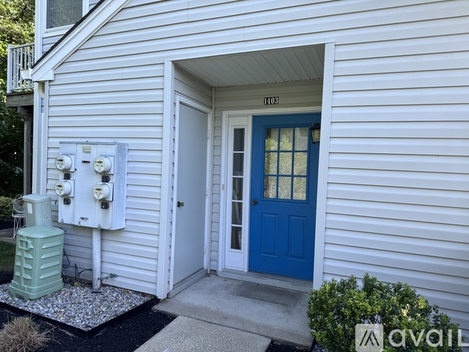 A white house with a blue door and a green tank.