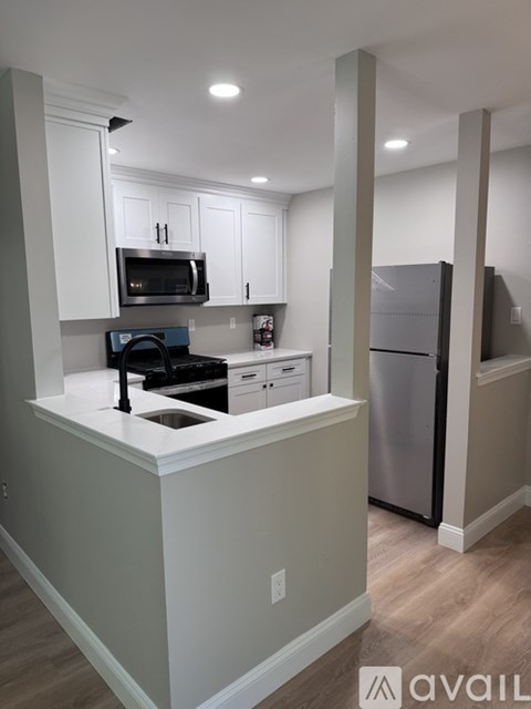 A kitchen with white cabinets and a stainless steel refrigerator.