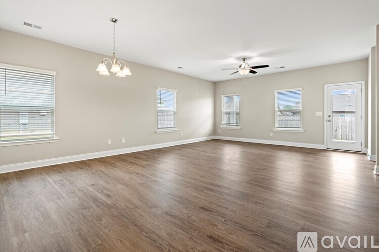 A spacious room with wood flooring and a ceiling fan.