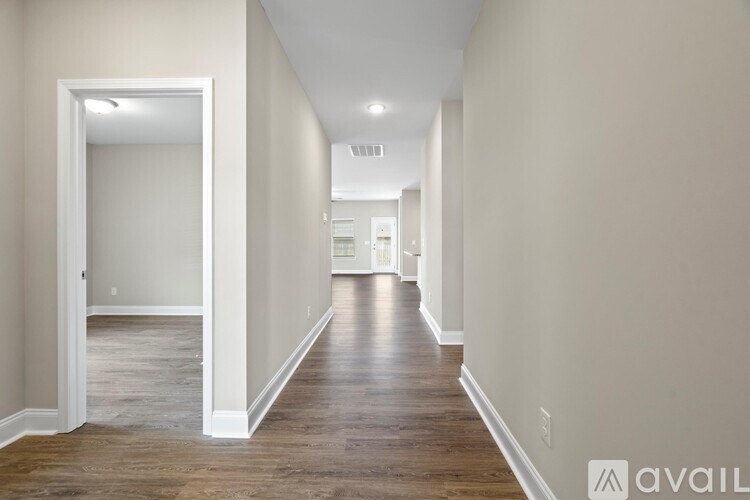 A long hallway with wood floors and white walls.