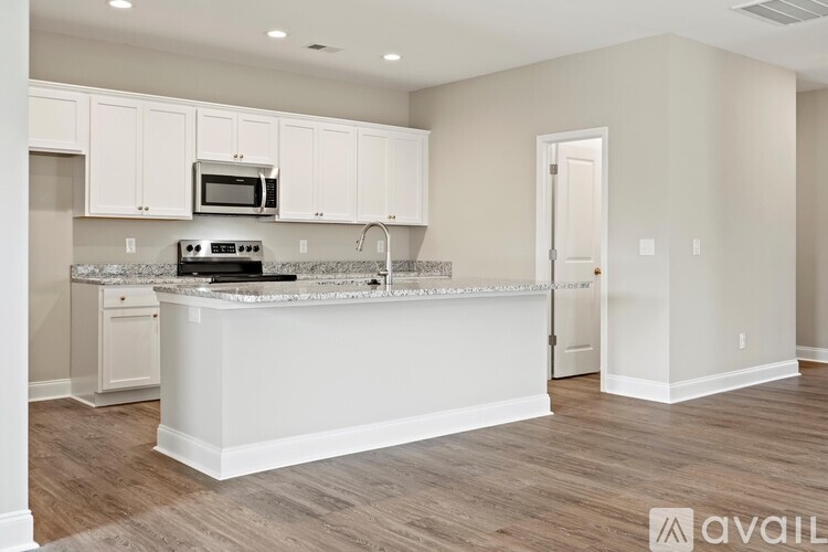 A kitchen with white cabinets and a marble countertop.