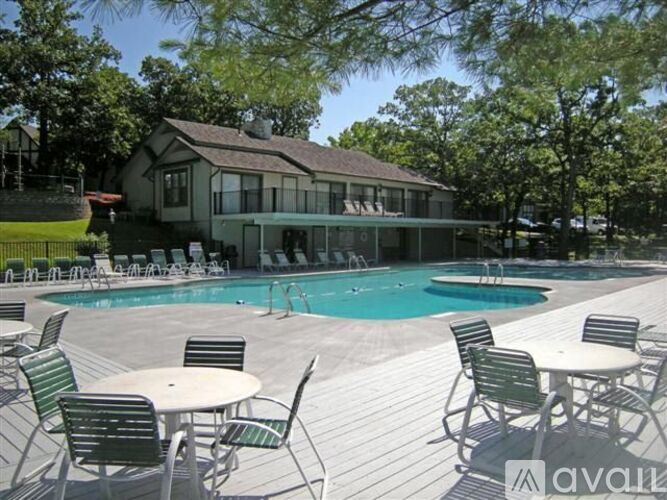 A pool with chairs and a house in the background.