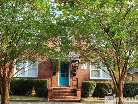 A house with a blue door is surrounded by green trees.