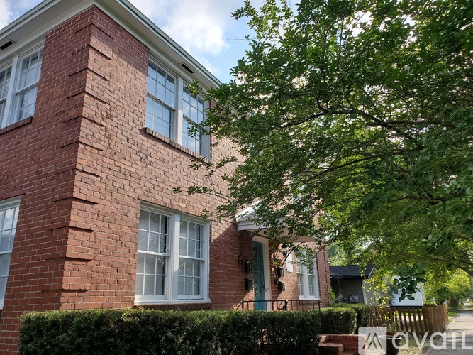 A red brick house with a green door and white windows.