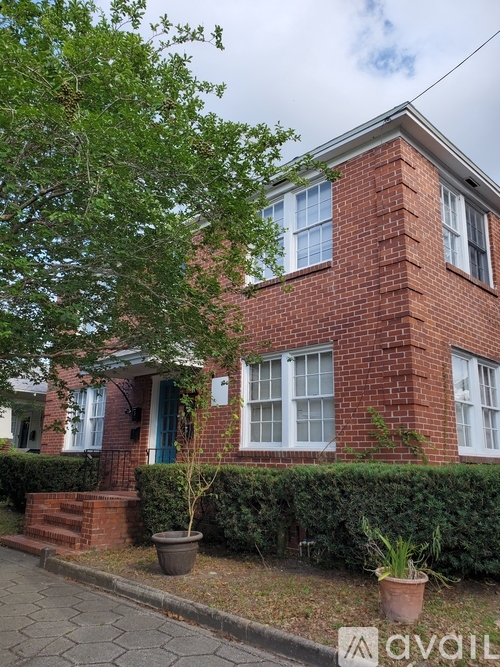 A red brick house with a green tree in front.