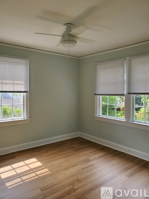 A room with a ceiling fan and two windows.