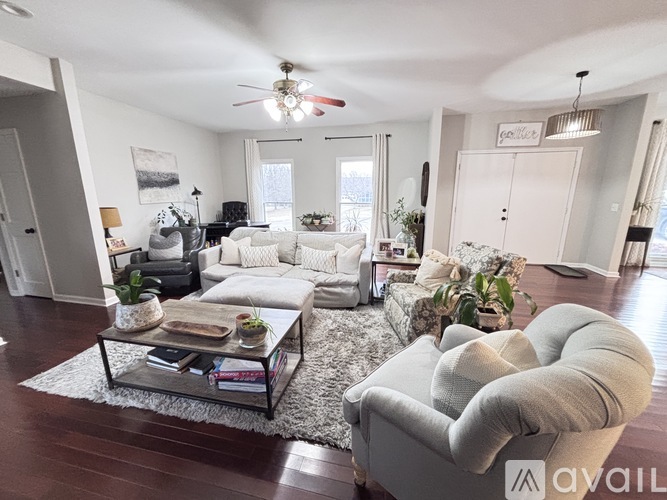 A living room with a white couch, a grey armchair, and a glass coffee table.