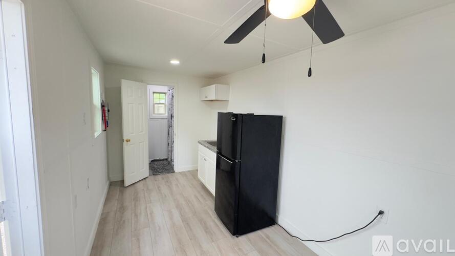 A kitchen with a black fridge and a ceiling fan.