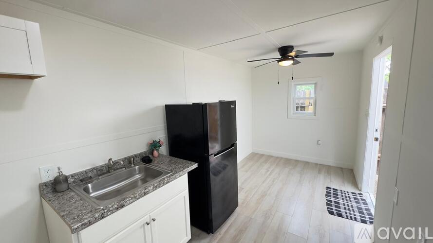 A kitchen with a black refrigerator and a sink with a granite countertop.