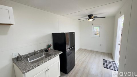 A kitchen with a black refrigerator and a sink with a granite countertop.