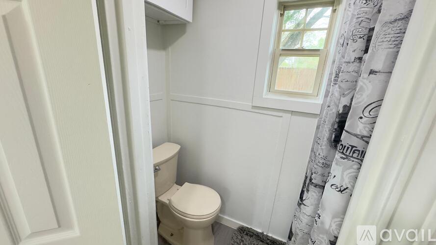 A white toilet in a small bathroom with a window.