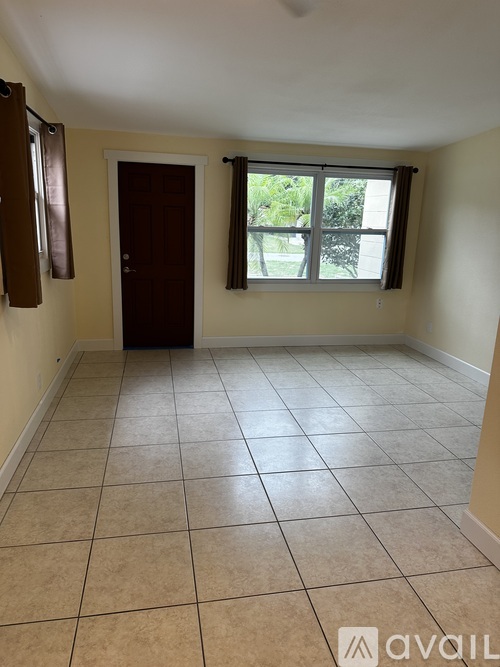 A room with a brown door and a window with a view of trees.