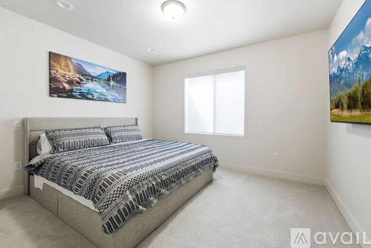 A bedroom with a large bed and two pictures on the wall.