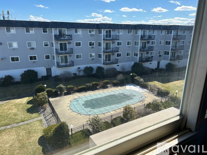 A view from a window of apartment buildings with a pool in the foreground.
