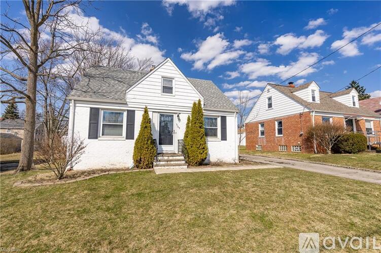 A house with a front yard and a tree in front of it.
