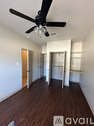 A room with a ceiling fan and wooden flooring.