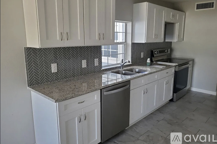 A kitchen with white cabinets and a granite countertop.