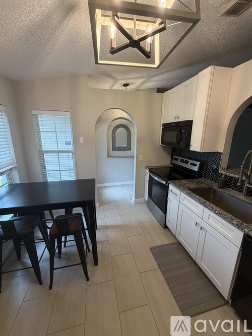 A kitchen with a table and chairs in the foreground and a microwave and oven in the background.