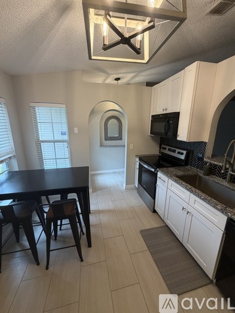 A kitchen with a table and chairs in the foreground and a microwave and oven in the background.
