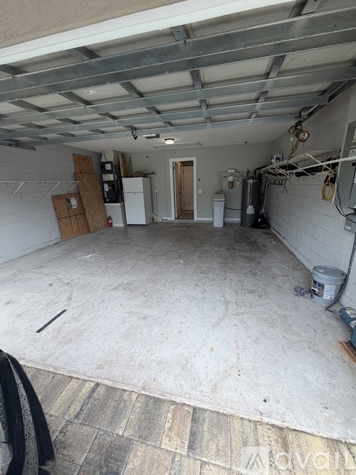 A spacious garage with a concrete floor and a white refrigerator in the corner.