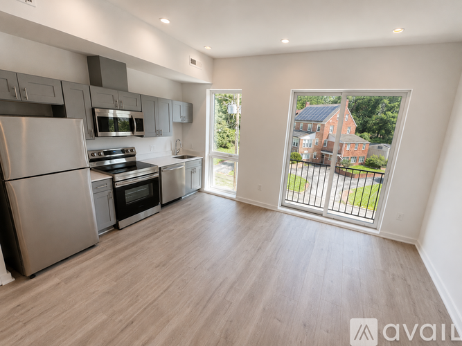 A modern kitchen with stainless steel appliances and a view of a red brick house through a sliding glass door.