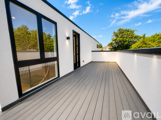 A balcony with wooden flooring and a white wall.