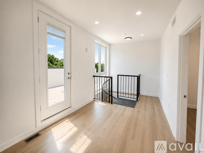 A spacious room with wooden flooring and a black railing.