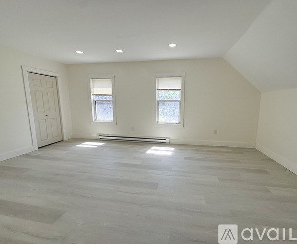A spacious room with a grey floor and two windows.