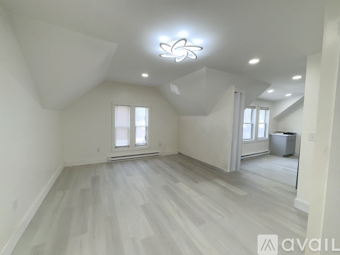 A spacious room with a large window and a trash bin.