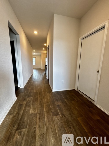 A hallway with wooden floors and white walls.