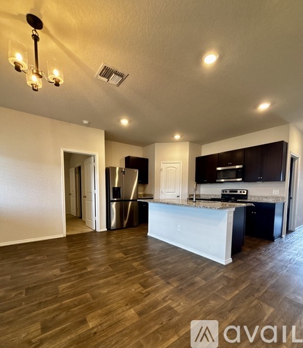 A kitchen with a white island and dark wood floors.