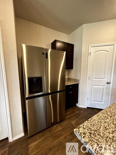 A stainless steel refrigerator with a black handle is in a kitchen.