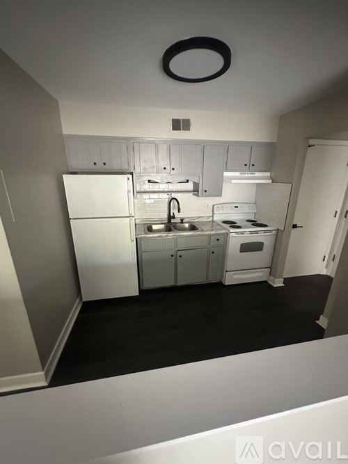 A small kitchen with white appliances and a black ceiling light.