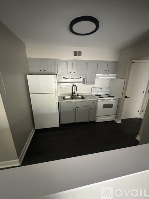 A small kitchen with white appliances and a black ceiling light.