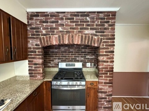 A kitchen with a brick fireplace and a stove top oven.