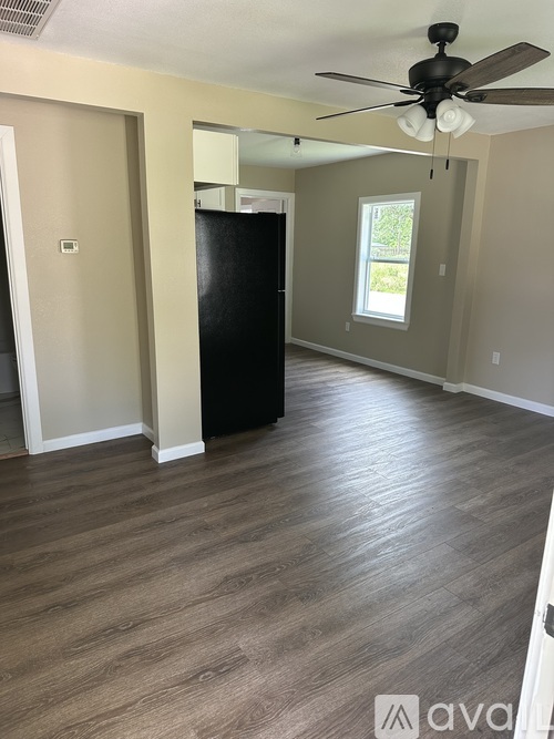 A room with a ceiling fan and a black refrigerator.