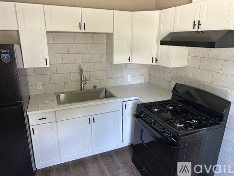 A kitchen with white cabinets and a black stove top oven.