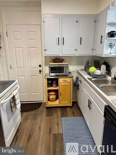 A kitchen with white cabinets and a wooden floor.