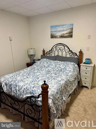 A bedroom with a bed, nightstand, lamp, and a painting on the wall.