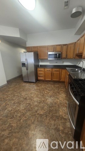 A kitchen with brown flooring and wooden cabinets.