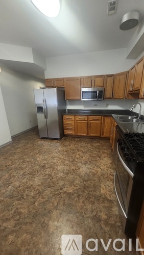 A kitchen with brown flooring and wooden cabinets.
