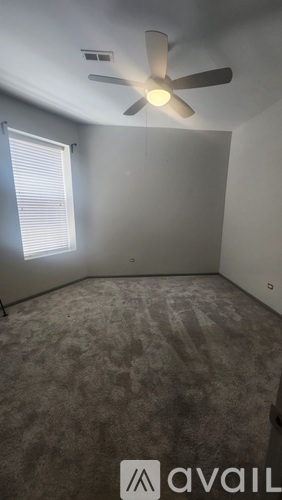 A room with a ceiling fan and a window with blinds.